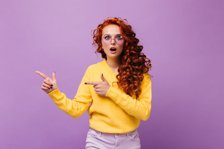 301 girl-yellow-sweater-lilac-glasses-looks-surprised-camera-isolated-wall